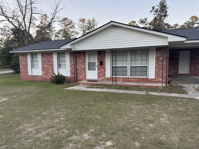 single story home featuring covered porch, brick siding, a front lawn, and an attached carport