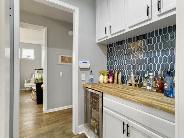 bar featuring beverage cooler, white cabinets, backsplash, and hardwood / wood-style flooring