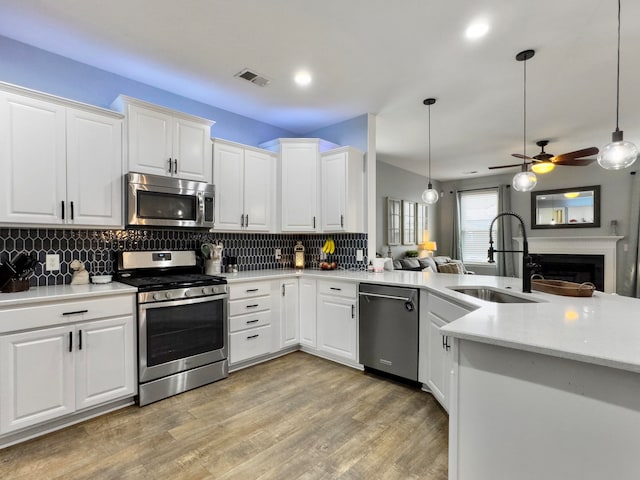 kitchen featuring pendant lighting, stainless steel appliances, ceiling fan, and white cabinets