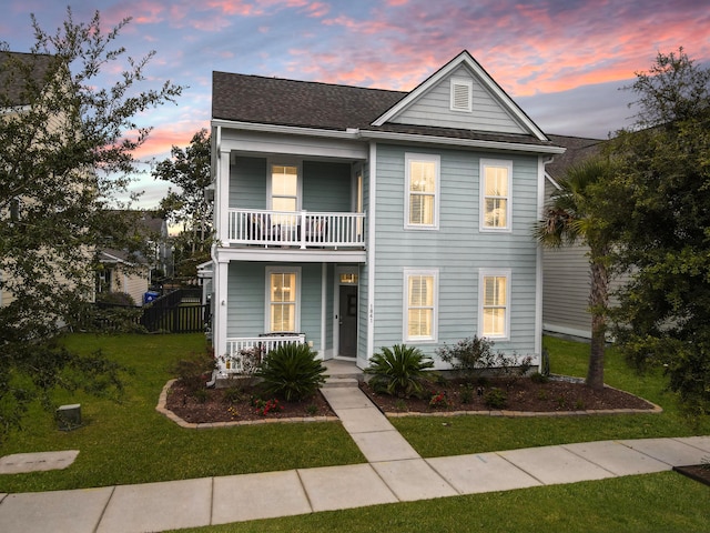 view of front facade featuring a balcony, a lawn, and a porch