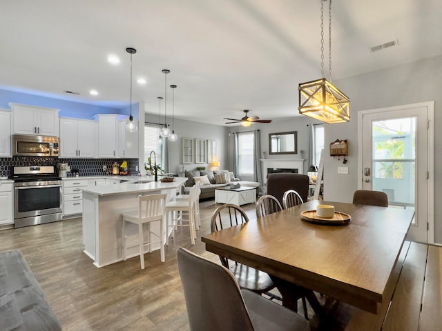 dining area with wood-type flooring, sink, and ceiling fan