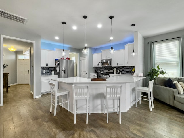 kitchen with appliances with stainless steel finishes, decorative backsplash, dark hardwood / wood-style flooring, and white cabinetry