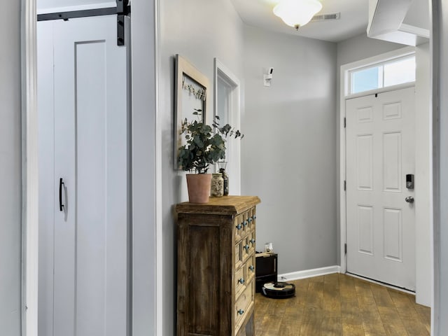 foyer with dark wood-type flooring and a barn door