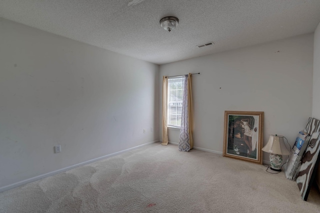 carpeted empty room with baseboards, visible vents, and a textured ceiling