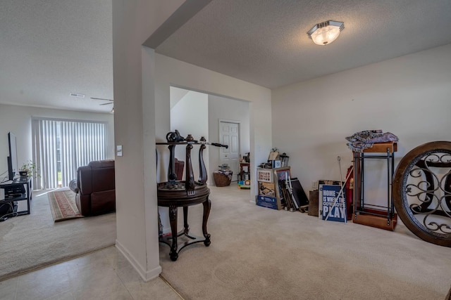 interior space with a textured ceiling, carpet flooring, and baseboards
