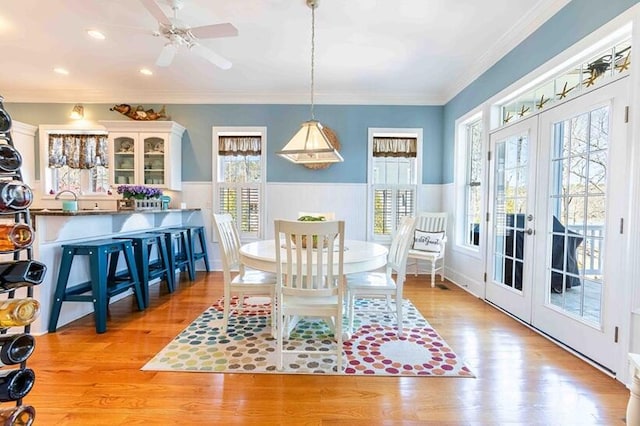 dining space with french doors, wainscoting, and light wood finished floors