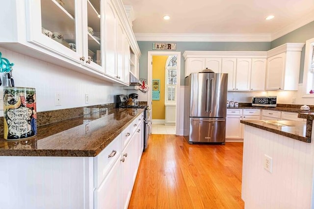 kitchen featuring stainless steel appliances, white cabinetry, ornamental molding, light wood-type flooring, and glass insert cabinets