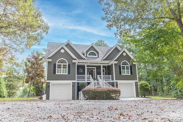 view of front of house with an attached garage, covered porch, and stairs