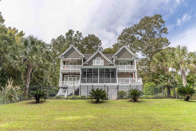 rear view of property featuring a balcony, fence, a sunroom, stairway, and a lawn