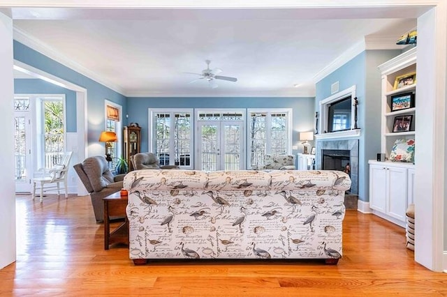 living area with light wood-style flooring, crown molding, and a wealth of natural light