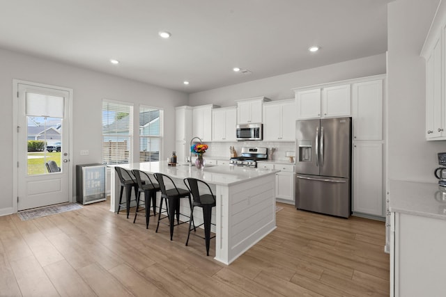 238 Bird Song Path, Summerville, SC 29485 - kitchen featuring stainless steel appliances, decorative backsplash, light countertops, a kitchen island with sink, and white cabinets