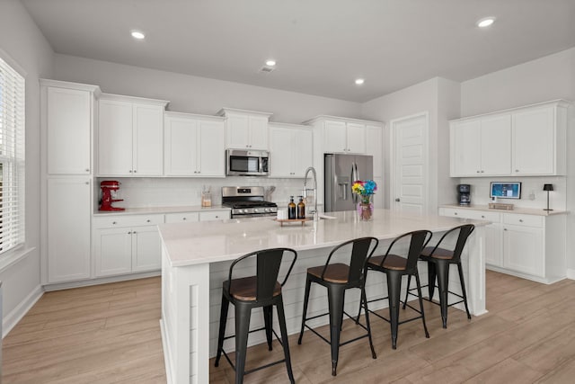 238 Bird Song Path, Summerville, SC 29485 - kitchen featuring appliances with stainless steel finishes, backsplash, a kitchen island with sink, light wood finished floors, and recessed lighting