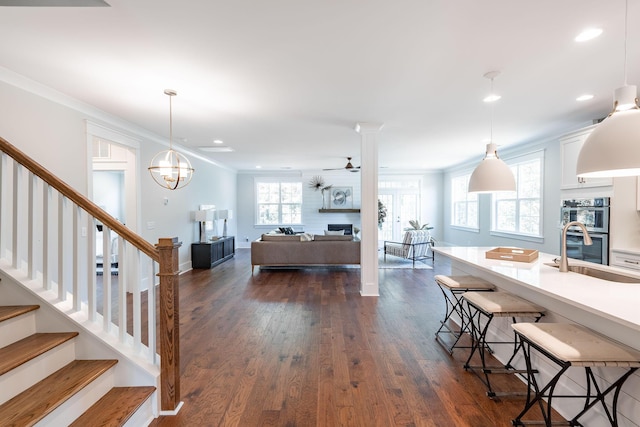 living room with dark wood-style flooring, a fireplace, crown molding, and stairway