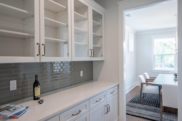 kitchen with tasteful backsplash, glass insert cabinets, and white cabinetry