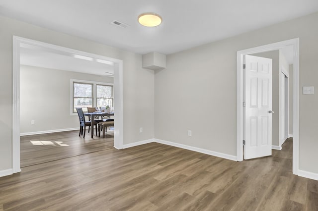 unfurnished room featuring wood finished floors, visible vents, and baseboards