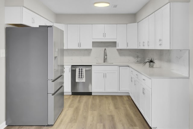 kitchen featuring light countertops, appliances with stainless steel finishes, a sink, and tasteful backsplash