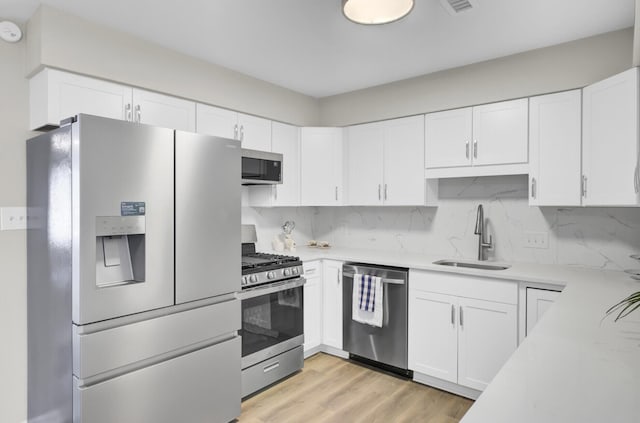 kitchen featuring decorative backsplash, stainless steel appliances, a sink, and light countertops