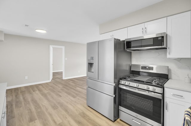 kitchen featuring stainless steel appliances, white cabinets, light countertops, light wood-type flooring, and backsplash