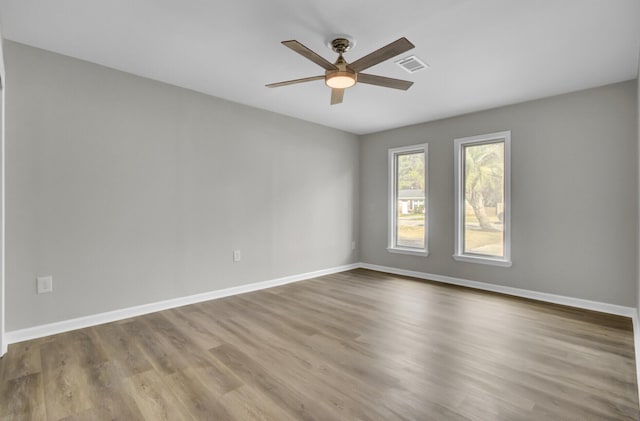 unfurnished room with a ceiling fan, baseboards, visible vents, and wood finished floors