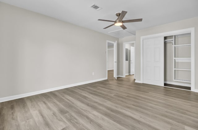 unfurnished bedroom with baseboards, a closet, visible vents, and wood finished floors