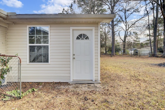 doorway to property featuring a lawn and fence