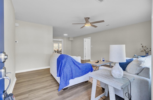 living area with a ceiling fan, visible vents, baseboards, and wood finished floors