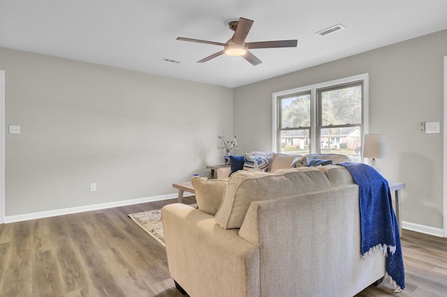 living area with a ceiling fan, baseboards, visible vents, and wood finished floors