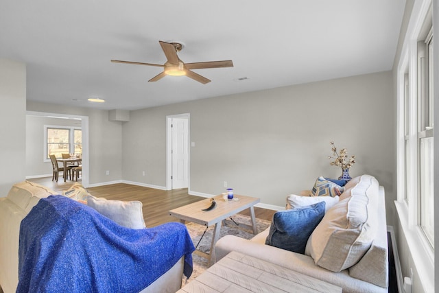 living area featuring ceiling fan, baseboards, and wood finished floors