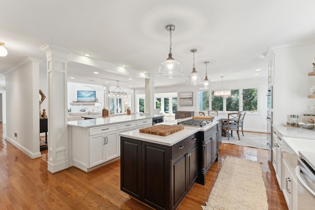 kitchen featuring appliances with stainless steel finishes, light wood-type flooring, decorative light fixtures, a center island, and white cabinetry