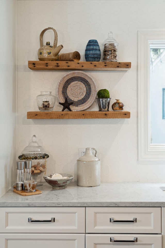 bar with decorative backsplash, light stone countertops, and white cabinetry