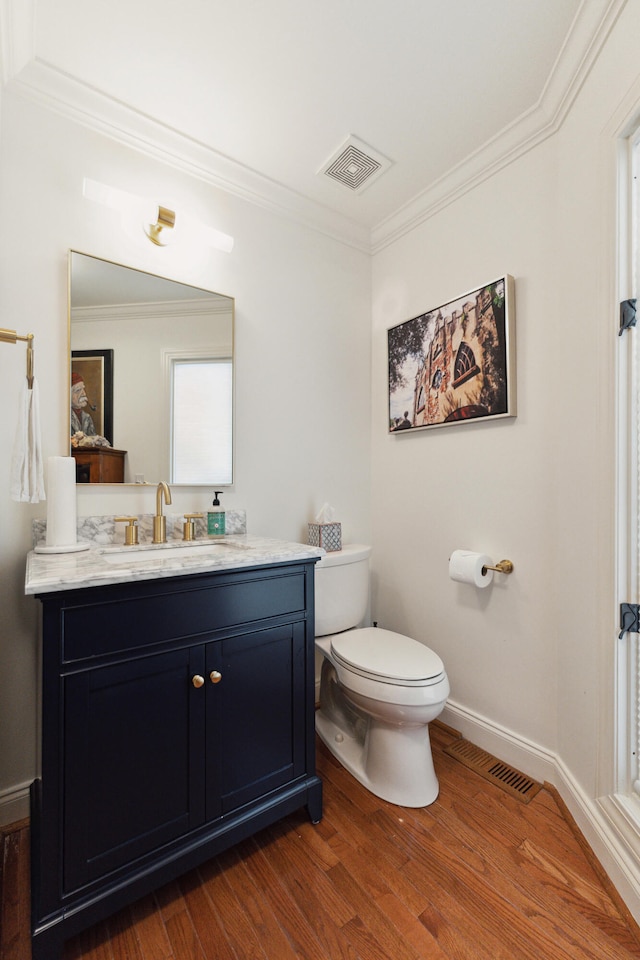 bathroom featuring toilet, vanity, wood-type flooring, and ornamental molding