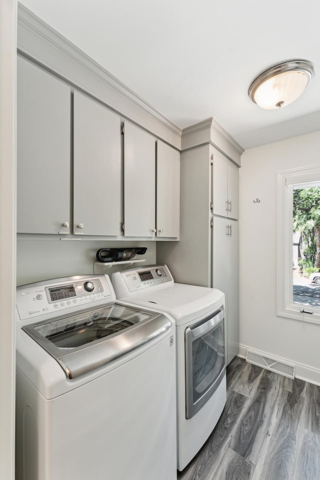 clothes washing area with washer and dryer, cabinets, and dark wood-type flooring