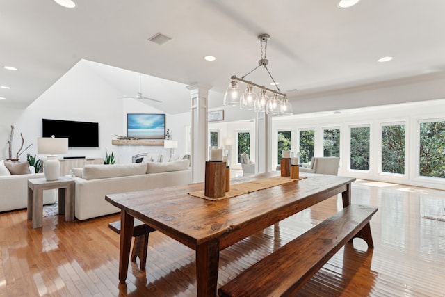 dining area featuring ceiling fan, light hardwood / wood-style floors, decorative columns, and vaulted ceiling