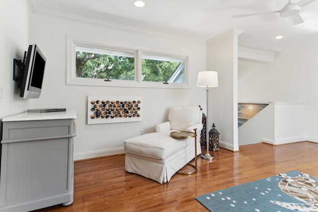 living area featuring hardwood / wood-style flooring, ceiling fan, and ornamental molding