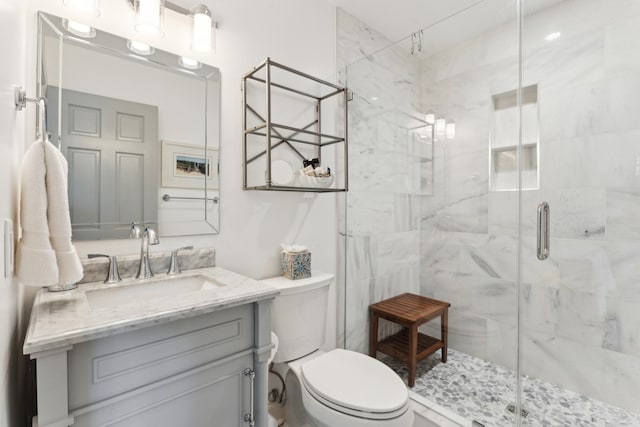 bathroom with a shower with door, vanity, and toilet