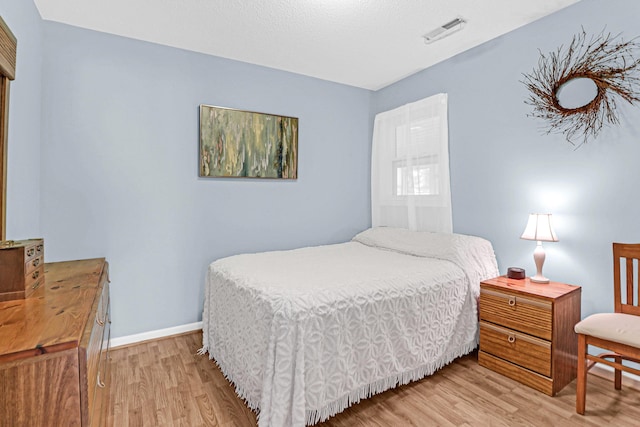 bedroom featuring baseboards, visible vents, and light wood finished floors