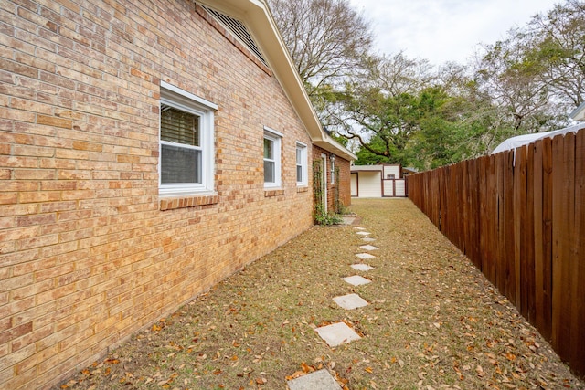 view of property exterior with a fenced backyard, an outdoor structure, and brick siding