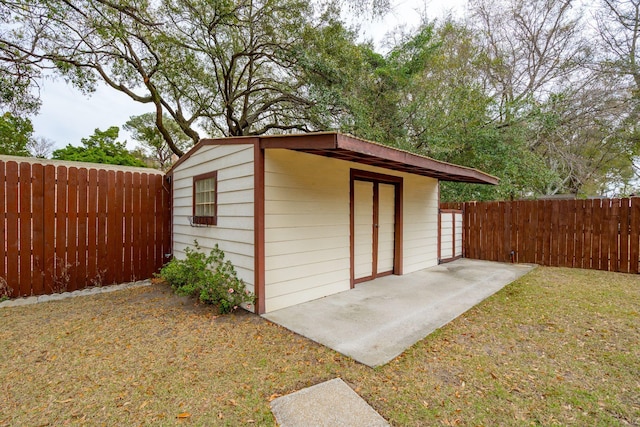 view of outdoor structure featuring a fenced backyard and an outbuilding