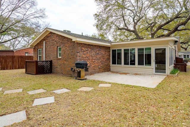 back of property featuring a patio area, brick siding, fence, and a lawn