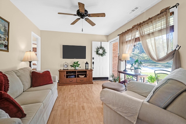 living room with visible vents, ceiling fan, and light wood-type flooring