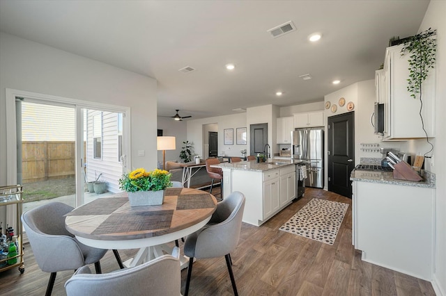 dining area featuring ceiling fan, sink, and wood-type flooring