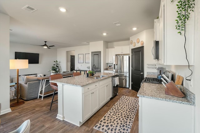 kitchen featuring stainless steel appliances, sink, white cabinetry, and a center island with sink