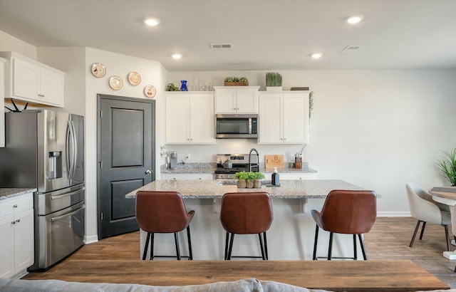 kitchen featuring white cabinets, stainless steel appliances, and an island with sink