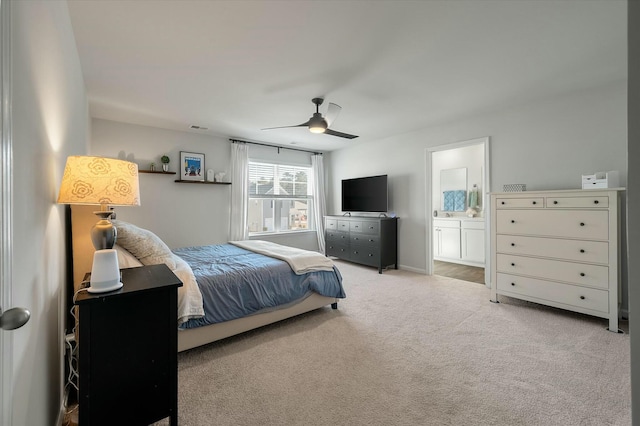 bedroom featuring ceiling fan, light colored carpet, and ensuite bath