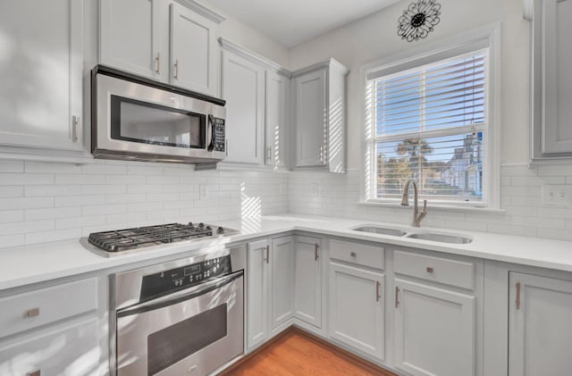 kitchen featuring decorative backsplash, sink, appliances with stainless steel finishes, and light hardwood / wood-style flooring