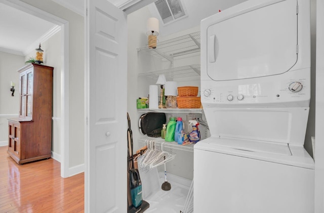 laundry room with crown molding, wood-type flooring, and stacked washer and clothes dryer