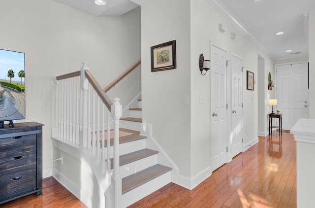 staircase with hardwood / wood-style flooring and ornamental molding