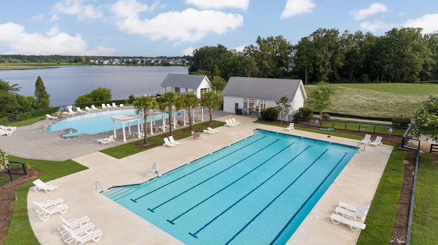 view of swimming pool with a patio area, a water view, and an outbuilding