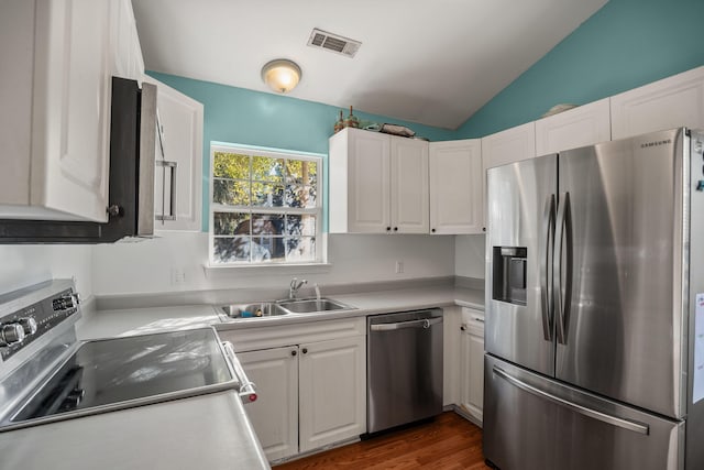 kitchen featuring appliances with stainless steel finishes, white cabinetry, dark hardwood / wood-style flooring, sink, and vaulted ceiling