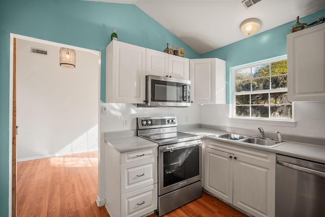 kitchen with vaulted ceiling, light hardwood / wood-style floors, sink, appliances with stainless steel finishes, and white cabinets